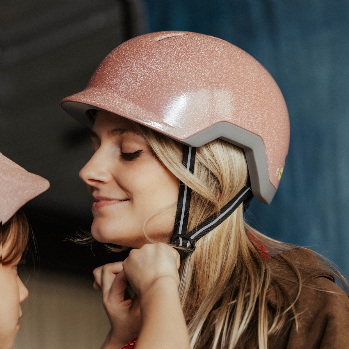 Een mama past een roze dames fietshelm en dochter kijkt mee hoe de sluiting werkt
