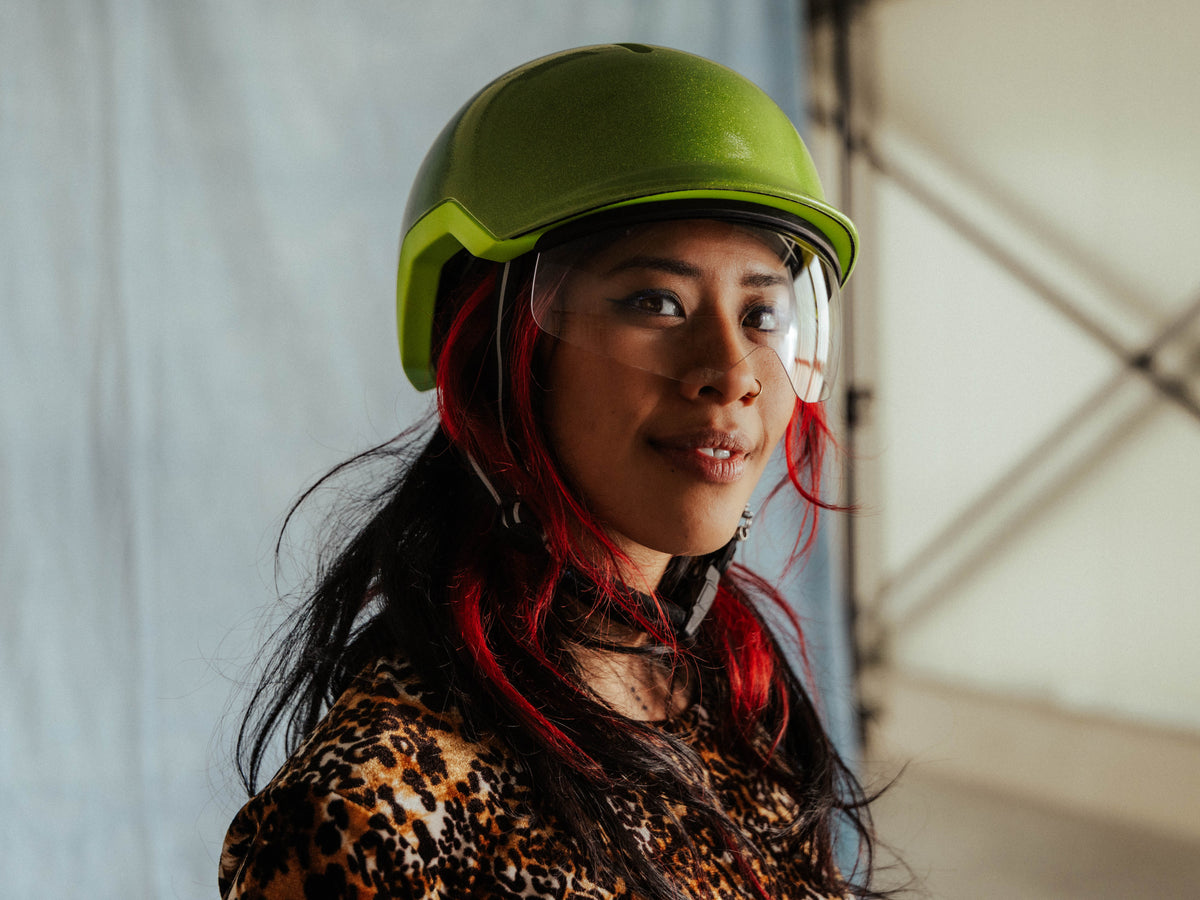 Vrouw met groene reflecterende fietshelm met magnetisch vizier voor speedpedelec